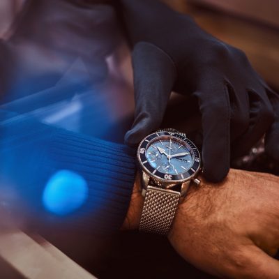 Close-up hands. Assistant helps the client to try on exclusive men's watches.