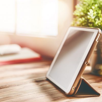 Office workplace with tablet on wood table near the window.
