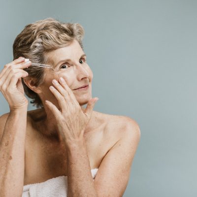 Senior woman applying moisturizer on her eye wrinkles