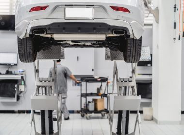 Back side of Car lifted in automobile service and Asian mechanic Checking and torch tire in maintainance service center which is a part of showroom, technician or professional work for customer concept